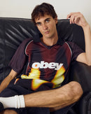 Obey Blurred Soccer Jersey Burnt Red Multi, sportief colorblock shirt van 100% polyester met rib V-hals kraag en Obey screen print, relaxed fit, maten S-XXL, verkrijgbaar bij Revert 95 Haarlem