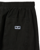 Obey Theo Easy Pant in Black Faded Wash, 100% cotton 6.5 oz lichtgewicht regular fit tapered leg broek met elastic waistband rounded drawcord faux fly on-seam front pockets en back patch pockets in subtiel worn-in zwarte kleur, verkrijgbaar bij Revert 95 Haarlem