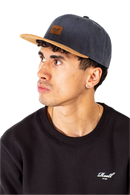 Reell Suede Cap, 80% cotton 20% suede 6-panel ball cap geïnspireerd op jaren 50 stijlen met flat suede rand aan klep kleur-geblokeerd design embossed Reell Script Logo Patch op voorkant en script logo flag snapback closure one size fits most, verkrijgbaar bij Revert 95 Haarlem