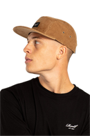 Reell 5-Panel Cap Cord, 100% cotton corduroy relaxed 5-panel snapback met structural brim stitching Reell woven logo patch op voorkant adjustable snapback closure met logo flag en woven brand label verkrijgbaar in Copper Brown Cord Hedge Cord en Black, verkrijgbaar bij Revert 95 Haarlem