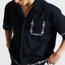 HUF Pinstripe Embroidered Resort Shirt in Black, 100% cotton 150G camp collar short sleeve resort shirt met pinstripe embroidery op linker borstzak zoom en beide mouwen button-down front branded buttons side vent slits en relaxed fit, verkrijgbaar bij Revert 95 Haarlem
