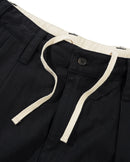 Butter Goods Pleated Trousers in Washed Black, 100% cotton herringbone twill baggy fit broek met dubbele plooien op de voorkant welt pockets met flap en button closure en belt loops met internal drawcord, verkrijgbaar bij Revert 95 Haarlem